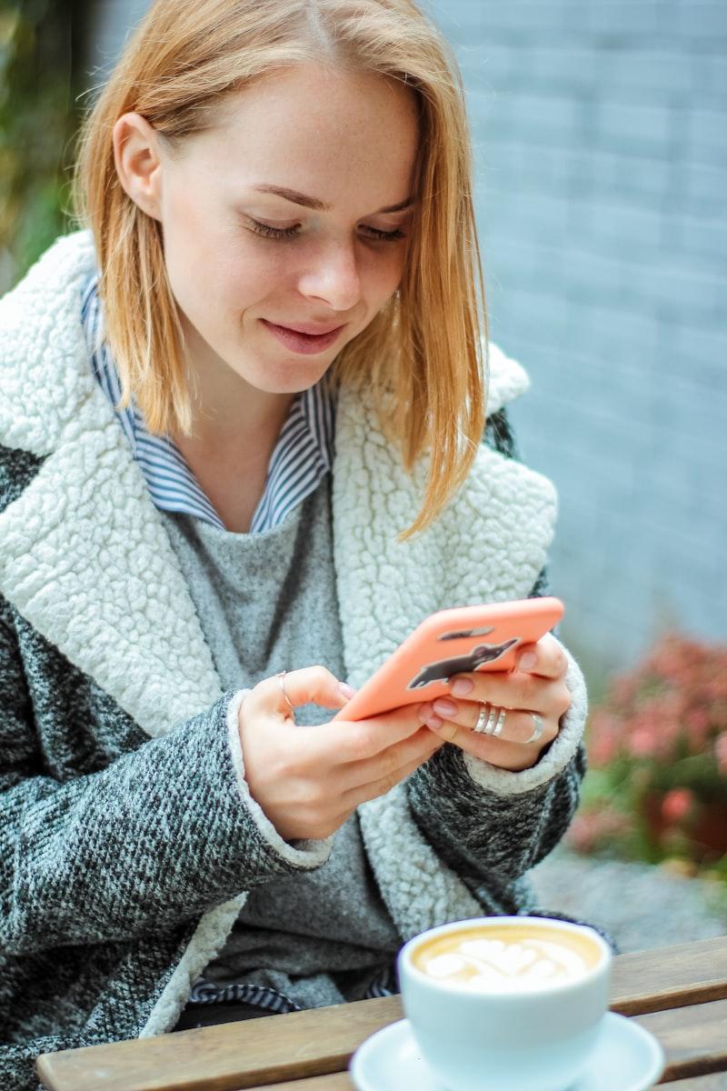 Person som ler medan de skickar meddelanden på telefonen